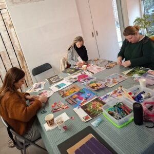  Participants autour d’une grande table créative, en train de découper et coller des images colorées lors de l’atelier Parenthèse colorée sur la symbolique de la couleur. 