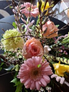 Gros plan sur un bouquet d’atelier floral associant gerbera rose, roses saumon et fleurs jaunes, réalisé lors de l’étape “Choix des fleurs et inspirations”